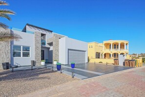 Une maison moderne à deux étages, dotée d’un garage, d’une allée et d’un jardin aménagé à l’avant.