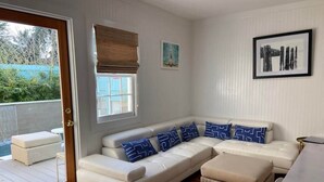 A modern living room with a white sectional sofa, blue patterned pillows, a wicker ottoman, and a dining table. - Home With Private Pool 'The Blue Lagoon' (Charleston)
