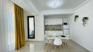 A modern kitchen with white cabinets, a microwave, and a small dining area with a table and chairs. - Alezzi Yaht Apartment With Sea View Near The Beach (MAMAIA SAT)