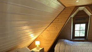 Ett mysigt sovrum på vinden med två sängar, träväggar och ett sluttande tak.