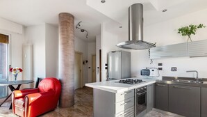 A modern kitchen with a central island, stainless steel appliances, and a red leather chair. - 051 Living apartment within walking distance of downtown and FS station (Bologna)