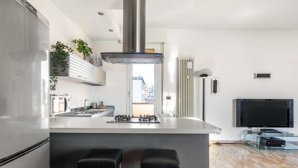 A modern kitchen with a central island, stainless steel appliances, and a flat-screen TV. - 051 Living apartment within walking distance of downtown and FS station (Bologna)