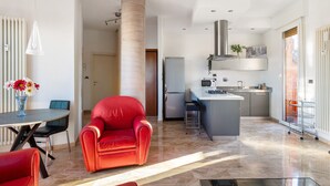 A modern kitchen with a central island, a red leather sofa, and a dining area with a table and chairs. - 051 Living apartment within walking distance of downtown and FS station (Bologna)