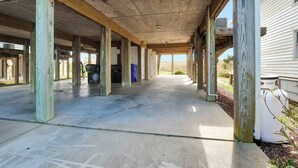 Un espacio cubierto y abierto con suelo de concreto y pilares de madera, que conduce a un edificio.