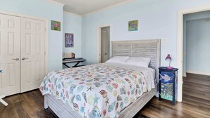 A bedroom with a bed, a desk, and a ceiling fan.