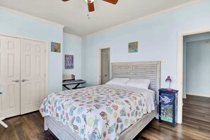 A bedroom with a bed, a desk, and a ceiling fan.
