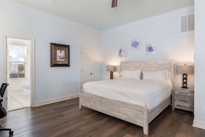 A bedroom with a large bed, two bedside tables, a door, and a window. - Saagara Thira (Carolina Beach)