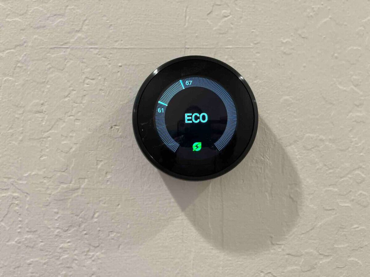 A circular device with the word "ECO" and a lightning bolt symbol, mounted on a textured wall.