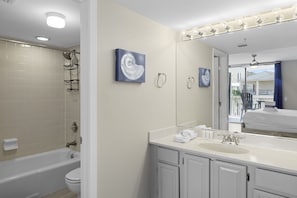 A bathroom with a bathtub, toilet, sink, and vanity. There are towels on the sink and a towel rack on the wall. - Mainsail 423 - Beachfront, Incredible Amenities, Pool, Beach Service Included! (Miramar Beach)
