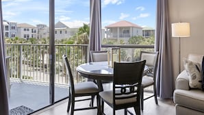 Ein Balkon mit rundem Tisch und Stühlen, einer Couch und einer Lampe.