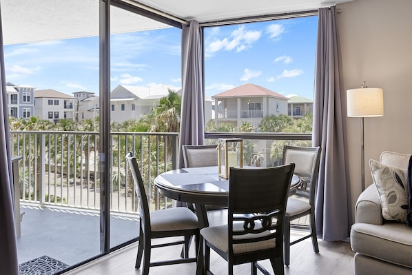 A balcony with a round table and chairs, a sofa, and a lamp. - Mainsail 423 - Beachfront, Incredible Amenities, Pool, Beach Service Included! (Miramar Beach)