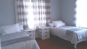 A bedroom with two single beds, white bedding, and a small white wicker side table. - Cozy Private Home @ Blue Moon Cottage in Historic Deland, Fl. (DeLand)
