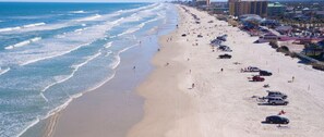 Ein Strand mit einer Reihe geparkter Autos und Gebäuden im Hintergrund.