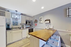 Una cocina moderna con armarios blancos, encimera de madera y horno empotrado.