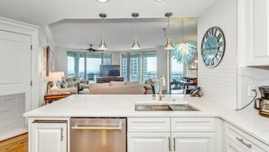 Una cocina moderna con armarios blancos, una isla grande con un lavamanos e iluminación colgante.