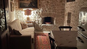 A cozy living room with a stone fireplace, a sofa, a dining table with chairs, and a rug. - An oasis of peace. (Gonnosnò)