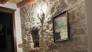 A stone wall with a framed picture, a wooden door, and two large ceramic pots. - An oasis of peace. (Gonnosnò)