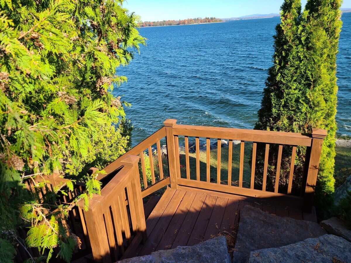 Um deck de madeira com guarda-corpo dando vista para a água.