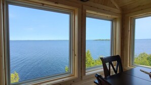 A room with large windows offering a view of a calm body of water and a distant island. - LoZa House rooftop SkyDeck lakefront  Pets Hot Tub (Plattsburgh)