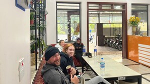 A reception area with a reception desk, seating area, and a view of parked motorcycles outside. - Ali Hostel Hà Giang (Ha Giang 1)