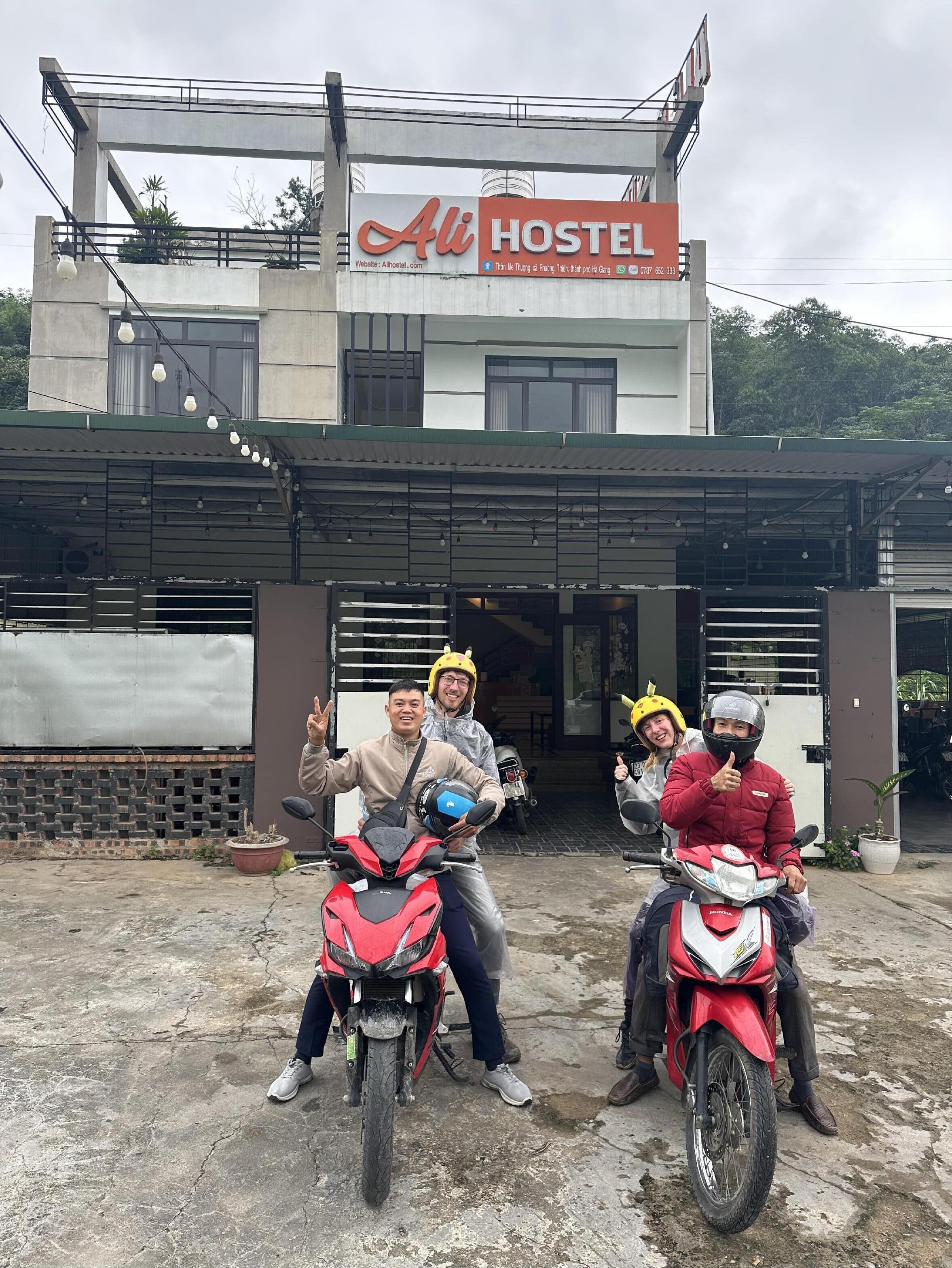 A hostel with a sign reading "Ali HOSTEL" and a contact number.