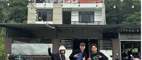 A hostel with a sign reading "Ali HOSTEL" and a motorcycle parked in front.