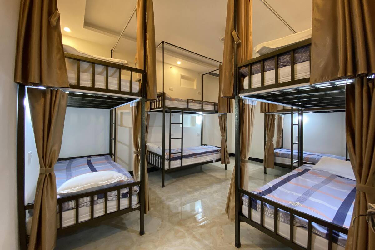 A room with bunk beds, each with a curtain. The room has a tiled floor and a skylight.