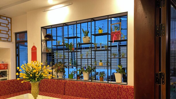 A room with a red patterned sofa, a glass coffee table, and a large window with a metal grid. - Ali Hostel Hà Giang (Ha Giang 1)