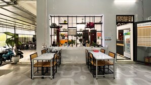 A spacious indoor area with a large window, two tables with chairs, and a refrigerator on the right. - Ali Hostel Hà Giang (Ha Giang 1)