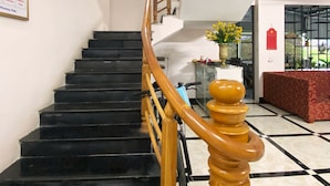 A staircase with black steps and a wooden handrail leading to an upper floor. - Ali Hostel Hà Giang (Ha Giang 1)