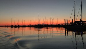 Un port de plaisance au coucher du soleil, où sont amarrés de nombreux voiliers.