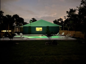 A modern house with a green roof, a swimming pool, and lounge chairs.