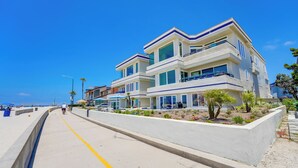 A multi-story beachfront property with balconies, a paved walkway, and a landscaped garden. - Oceanfront Paradise - AC, Private Patio, Gas Grill, Private Washer/Dryer! (San Diego)