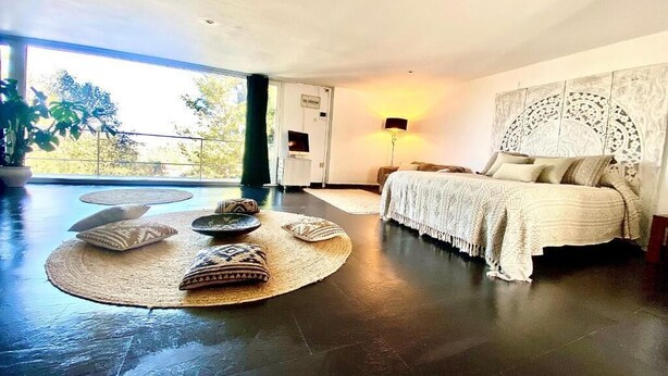 A modern bedroom with a large bed, a bedside lamp, and a view of the outdoors. - Spirit of Queen (Sant Cugat del Valles)