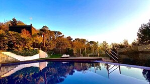 A clear blue sky above a swimming pool reflecting trees and a building. - Spirit of Queen (Sant Cugat del Valles)