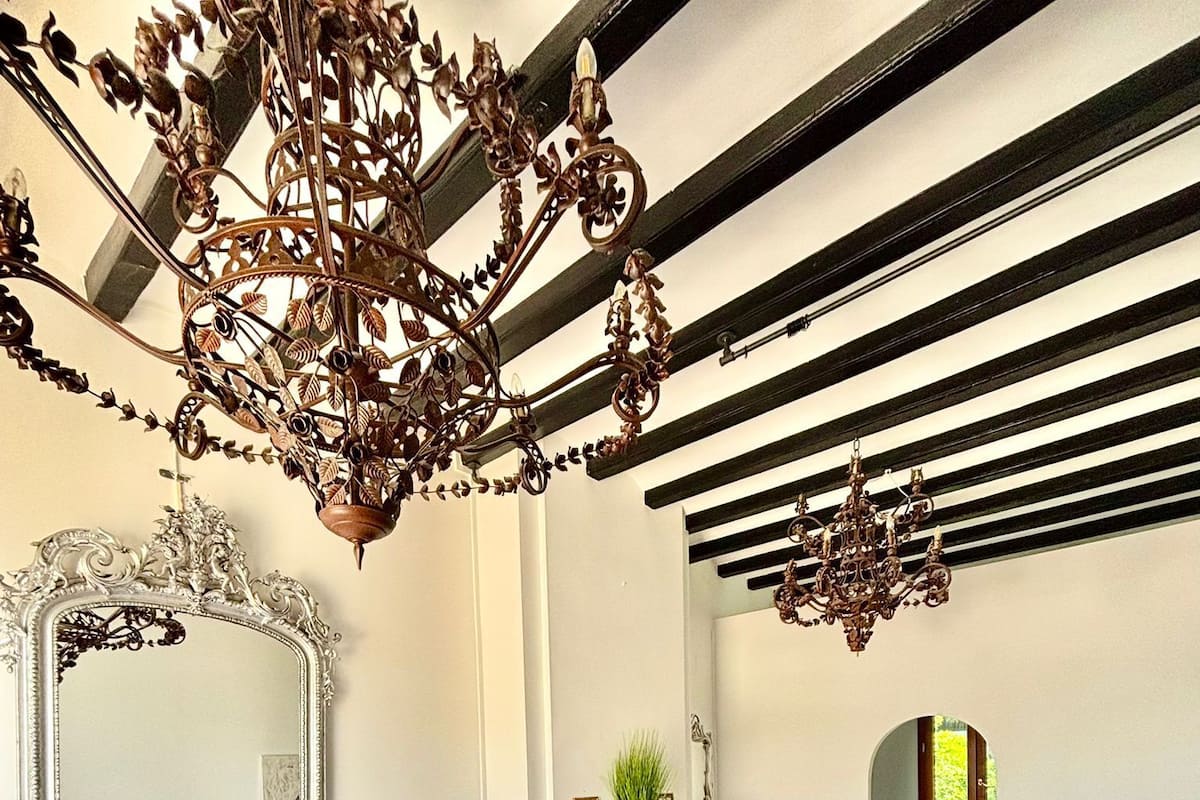 A spacious room with a large bed, a fireplace, a sofa, and a chandelier.