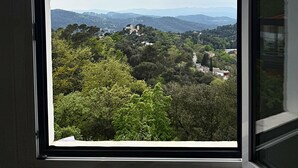 A window with a view of a hilly landscape, including trees and distant buildings. - Spirit of Queen (Sant Cugat del Valles)