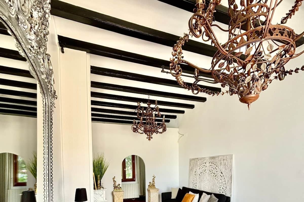 A spacious bedroom with a large bed, a modern chandelier, and a large mirror.