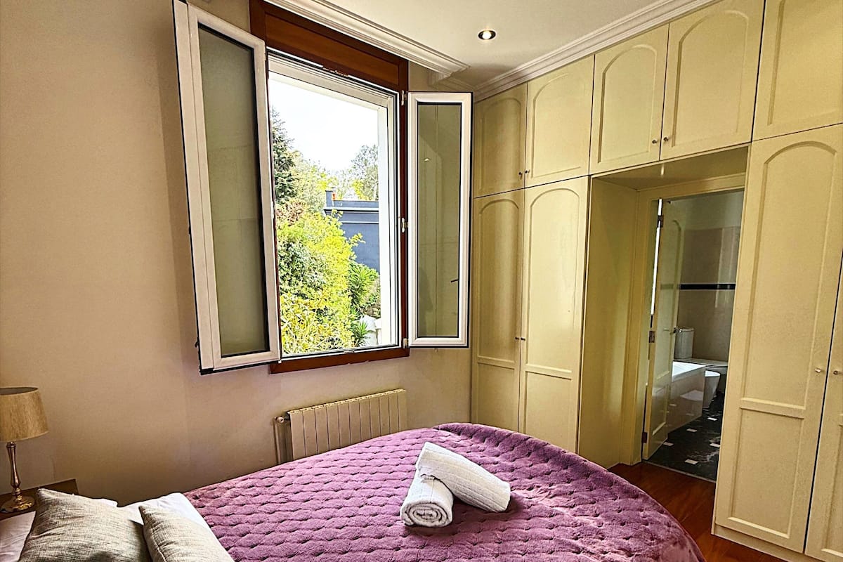 A bedroom with a large bed, a window, and a wardrobe.
