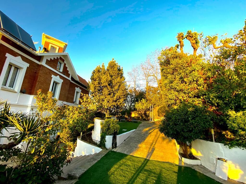 A residential property with a well-maintained lawn, a brick house, and a variety of trees and shrubs.