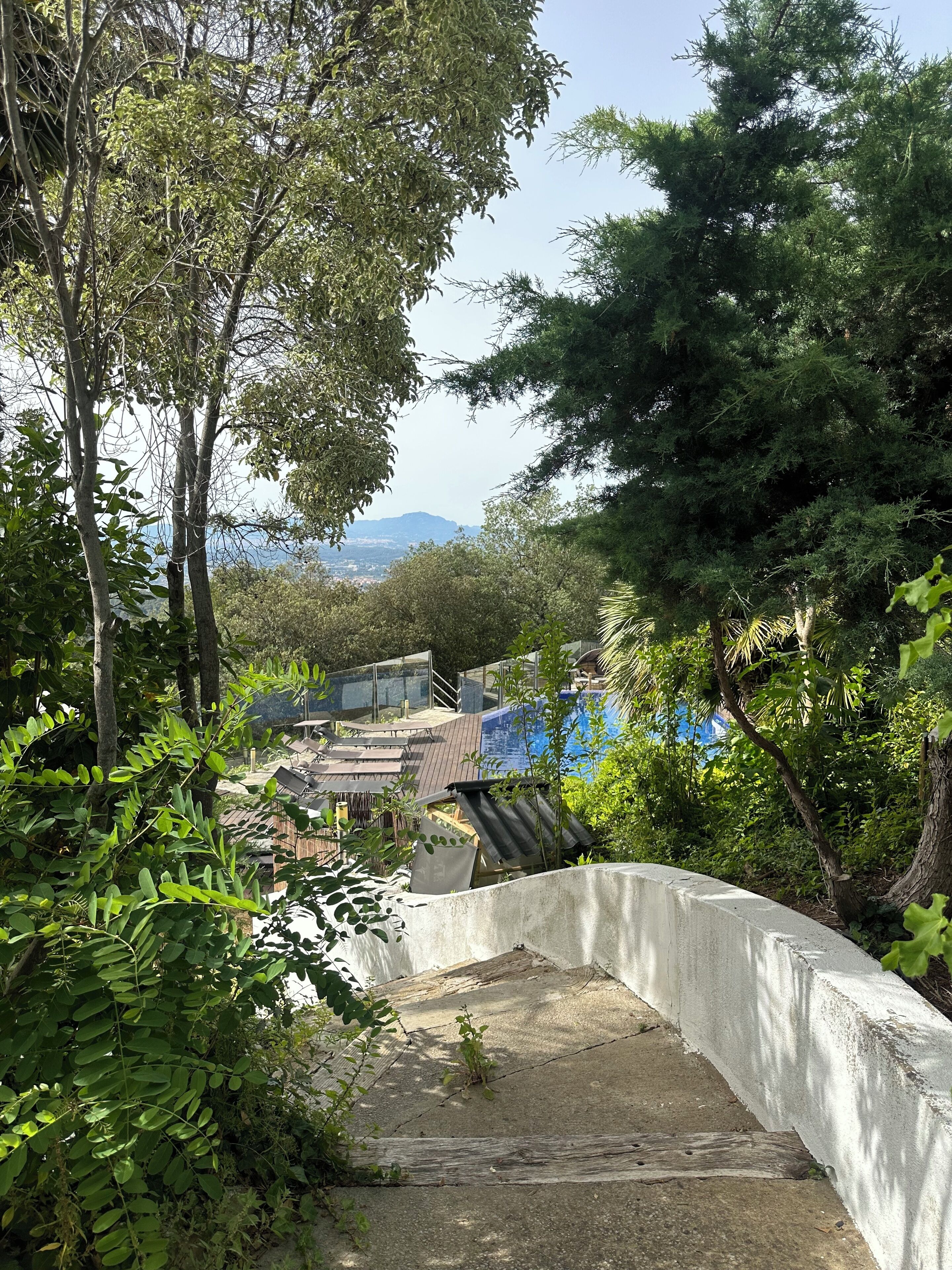Una escalera de concreto que desciende hacia una zona en la azotea con vistas a montañas distantes.