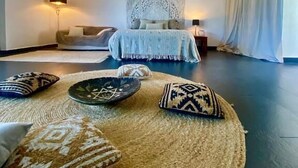 A bedroom with a bed, a large woven rug, and a headboard with a decorative panel. - Spirit of Queen (Sant Cugat del Valles)