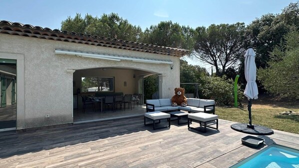 A patio with outdoor furniture, a pool, and a dining area with a view of the house.