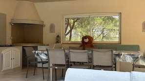 Ein Essbereich mit großem Fenster, einem Teddybären und einer Küche mit Gasherd.