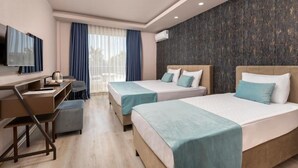 A hotel room with two beds, a desk, a TV, and a window with curtains. - Hotella Resort & Spa (Serik)