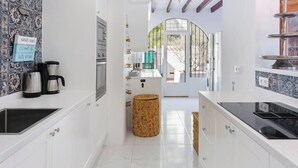 A modern kitchen with white cabinets, a coffee maker, and a wicker basket. - Village La Gomera (Jávea)