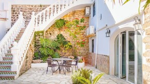 A stone staircase leading to a patio area with outdoor furniture and potted plants. - Village La Gomera (Jávea)