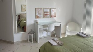 A bedroom with a bed, a desk, a chair, a mirror, and artwork on the wall. - APARTMENT BY THE SEA (Roseto degli Abruzzi)