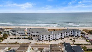 A beachfront hotel with multiple-story buildings, a parking lot, and a view of the ocean. - Blue Latitude - Oceanfront Condo (Carolina Beach)