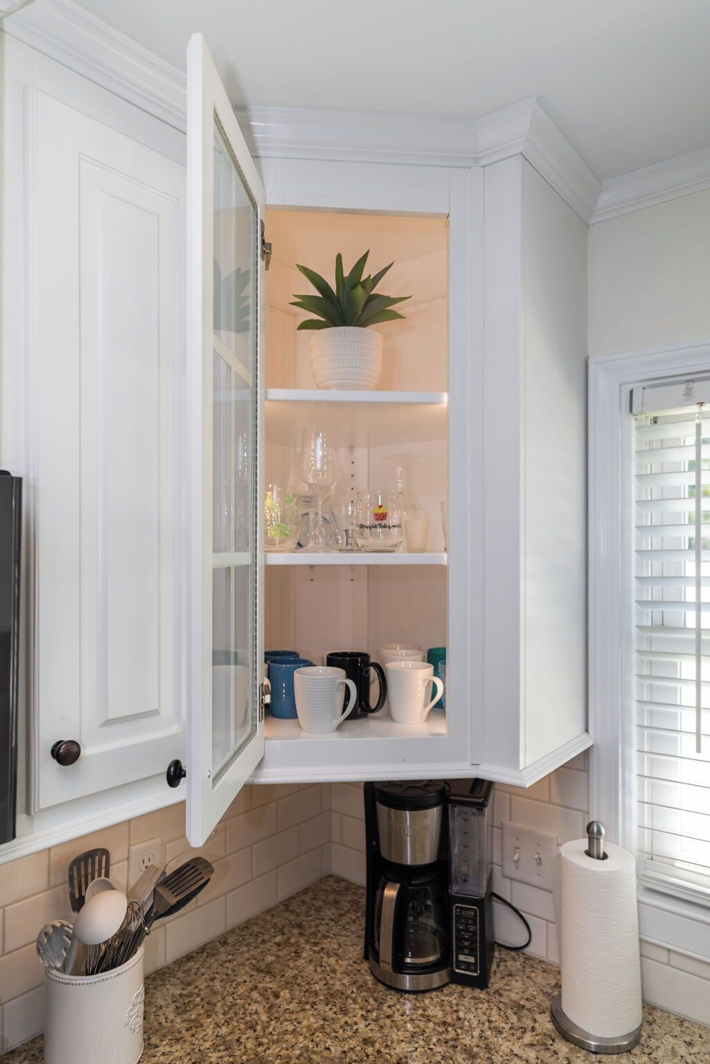 A kitchen with a built-in cabinet, a coffee maker, and a potted plant.